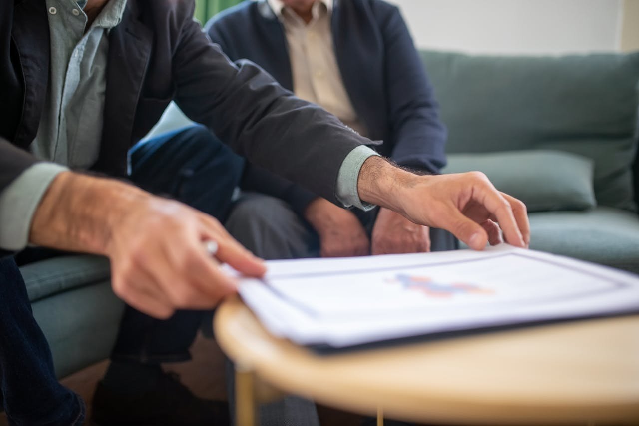 Home Two men discussing documents during a business meeting, focusing on paperwork.