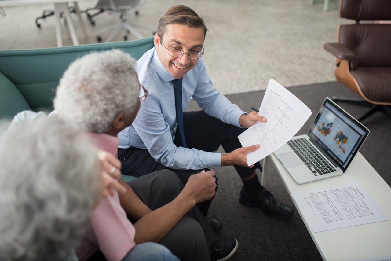 Offerings Financial advisor discussing documents with senior clients in an office setting, showcasing a collaborative consulting session.