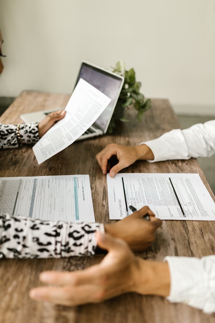 Offerings Two people reviewing documents at a wooden table during a business meeting.