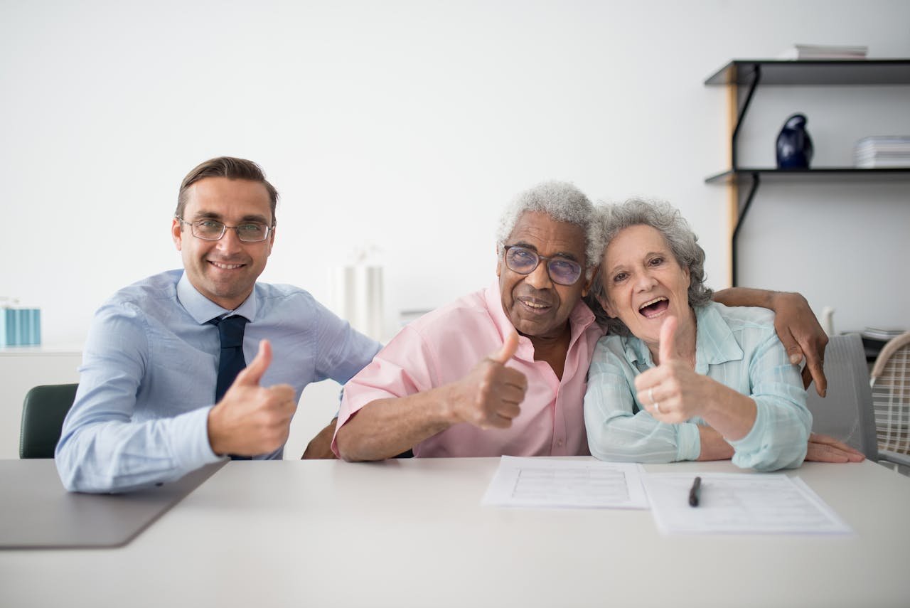 Offerings Elderly couple with consultant giving thumbs up in an office setting, showcasing positive interaction.